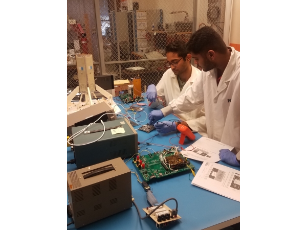 Two Students Wearing Lab Coats Working on Circuits