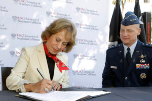 Presiden Carol L. Folt signing a paper