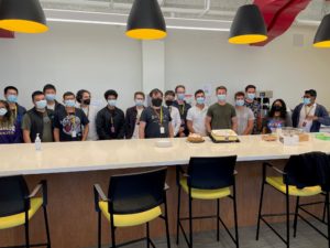 Group of students in dining area standing along a table with cakes