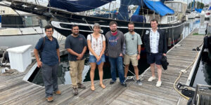 Group of people in marina on pier in front of boat