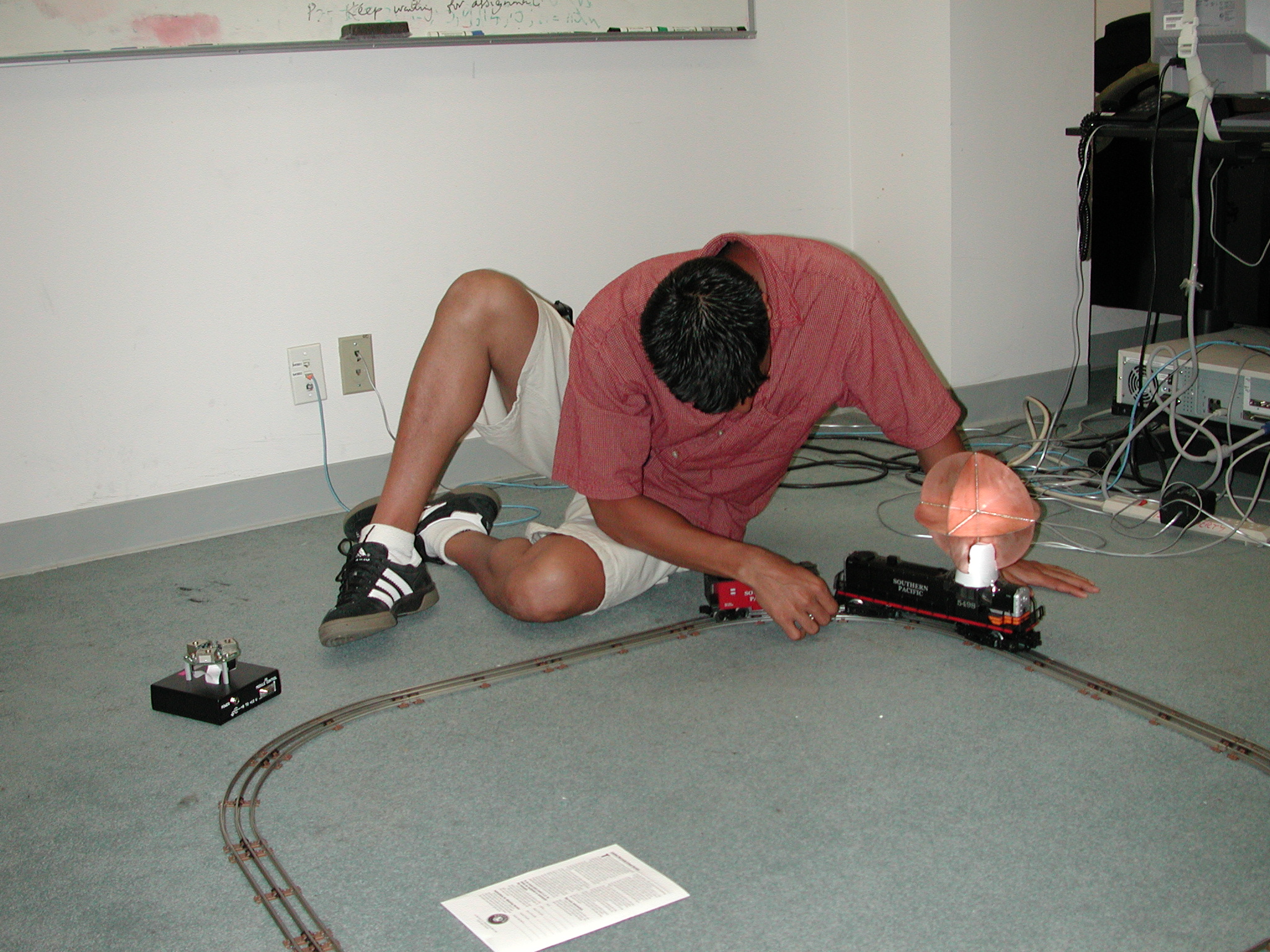 Person Ajusting Toy Train with Mounted Sensor