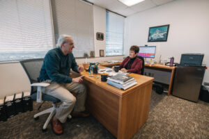 Two Researcher seated across office table engaged in conversation