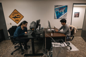 Two people working on computer in front of each other