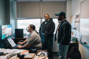 Group of three people staring at computer