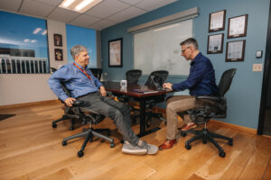 Two people seated by office table engaged in a conversation