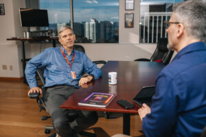 Two people seated by office table engaged in a conversation