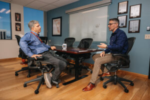 Two people seated by office table engaged in a conversation