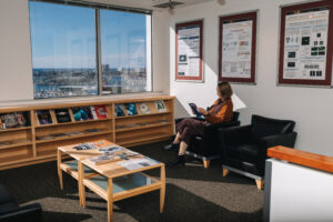 Person seated on couch in office lobby reading journal